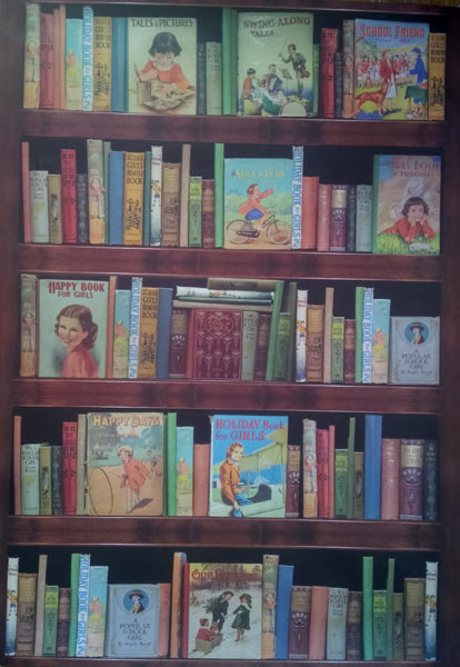 Wooden bookshelf filled with vintage children's books, some with illustrated covers featuring girls and stories.