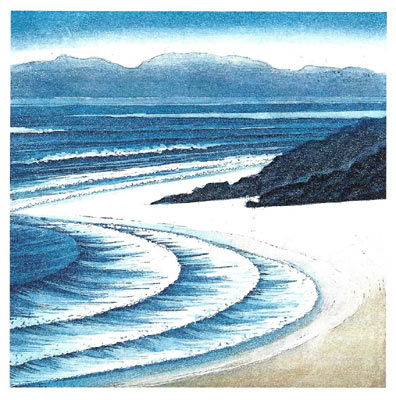 Curved ocean waves wash up on a sandy shore with dark rocks and distant hazy mountains.